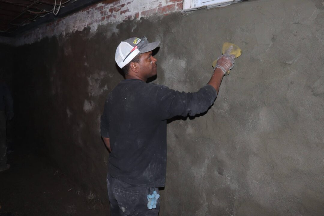 Drycrete Waterproofing employee parging a basement wall